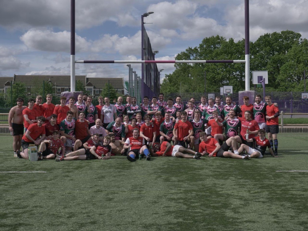 a group of alumni and current students gathered on a rugby pitch